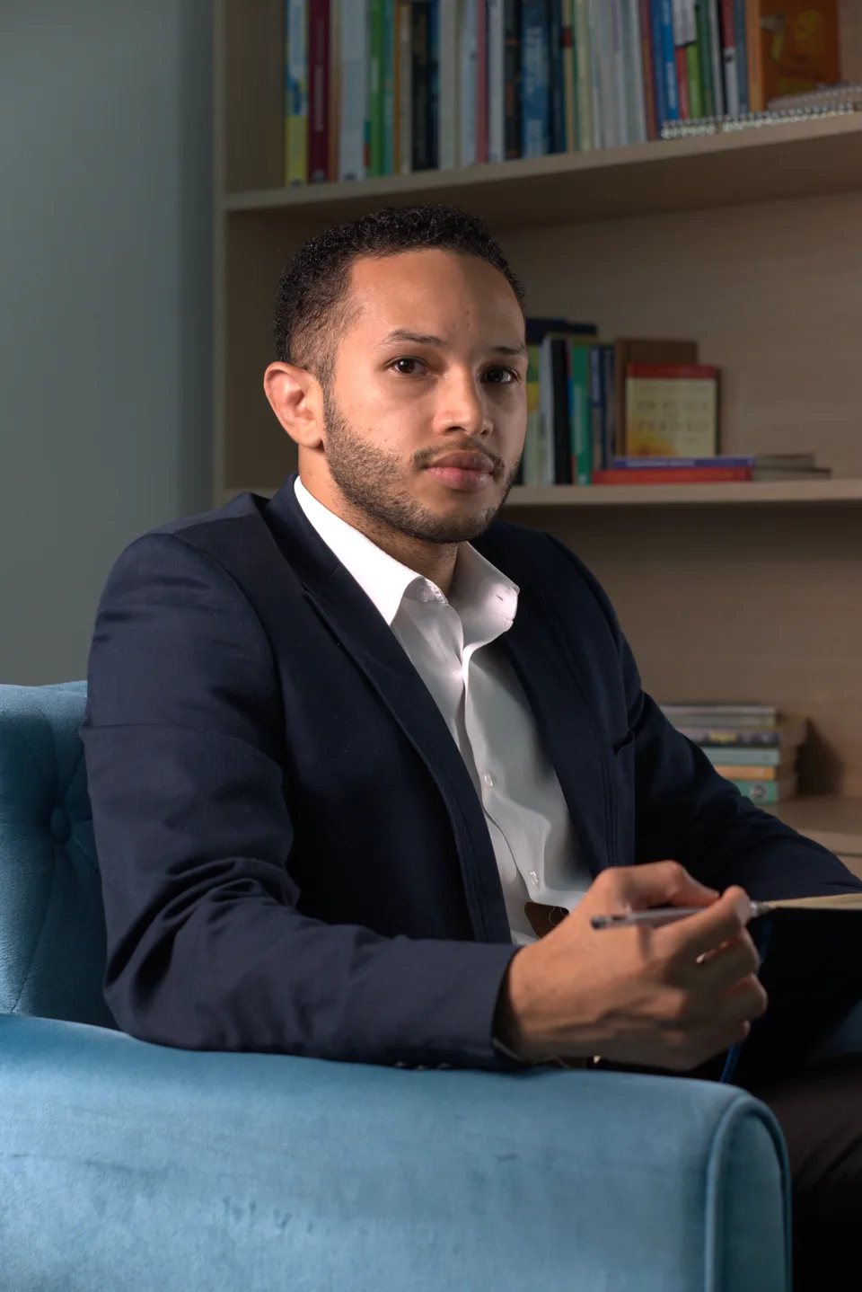 Caio Dourado, psicólogo, sentado com um caderno nas mãos